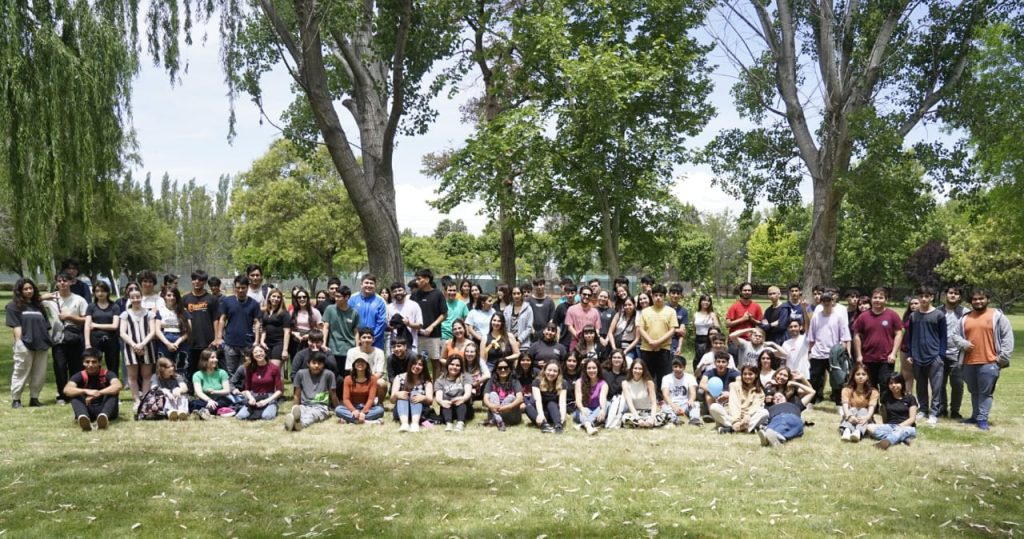 Cierre de becas en Neuquén con un grupo de jóvenes reunidos al aire libre en un entorno arbolado.