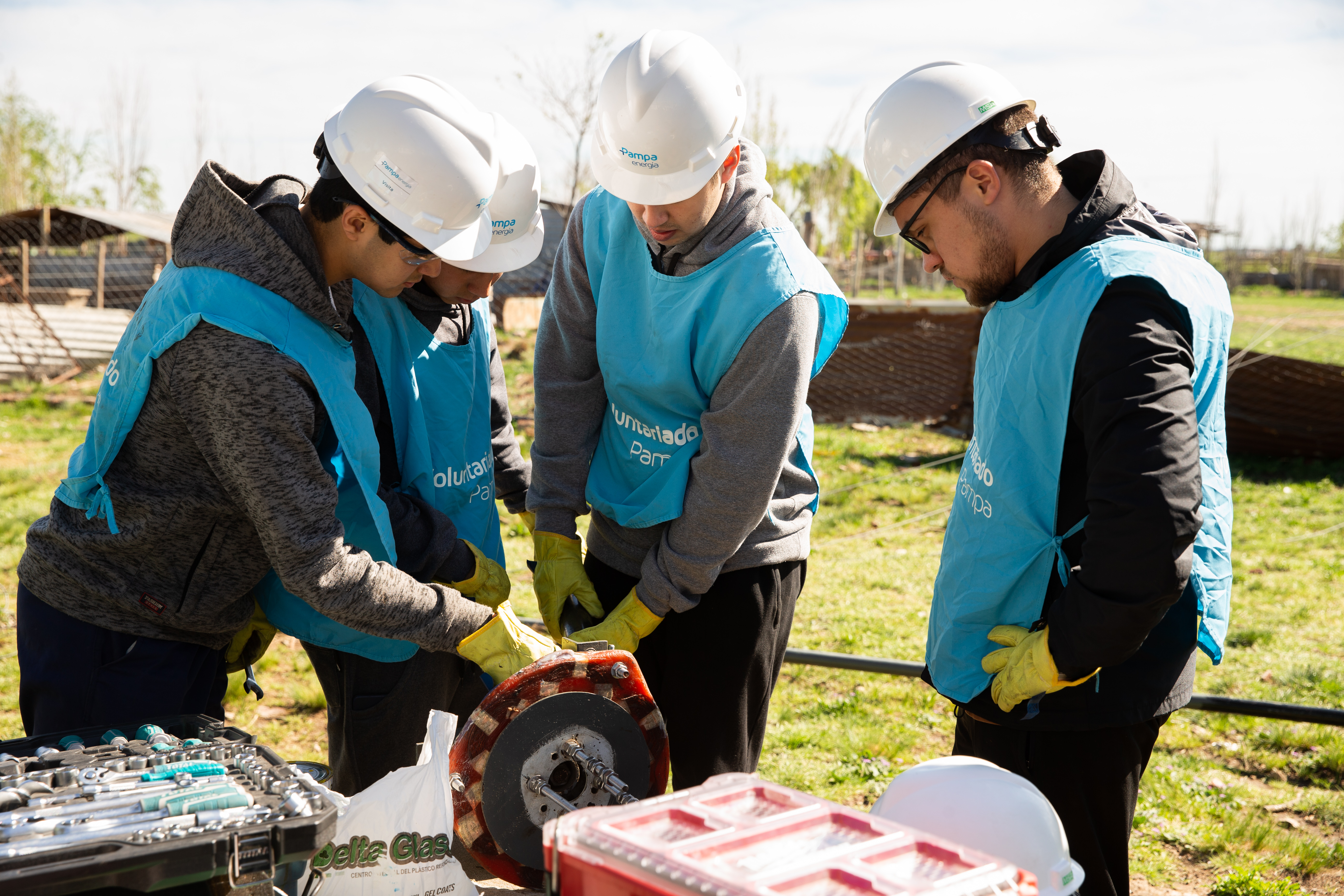 Voluntarios de la Fundación Pampa participan en prácticas energéticas, colaborando en tareas técnicas con equipamiento especializado al aire libre.