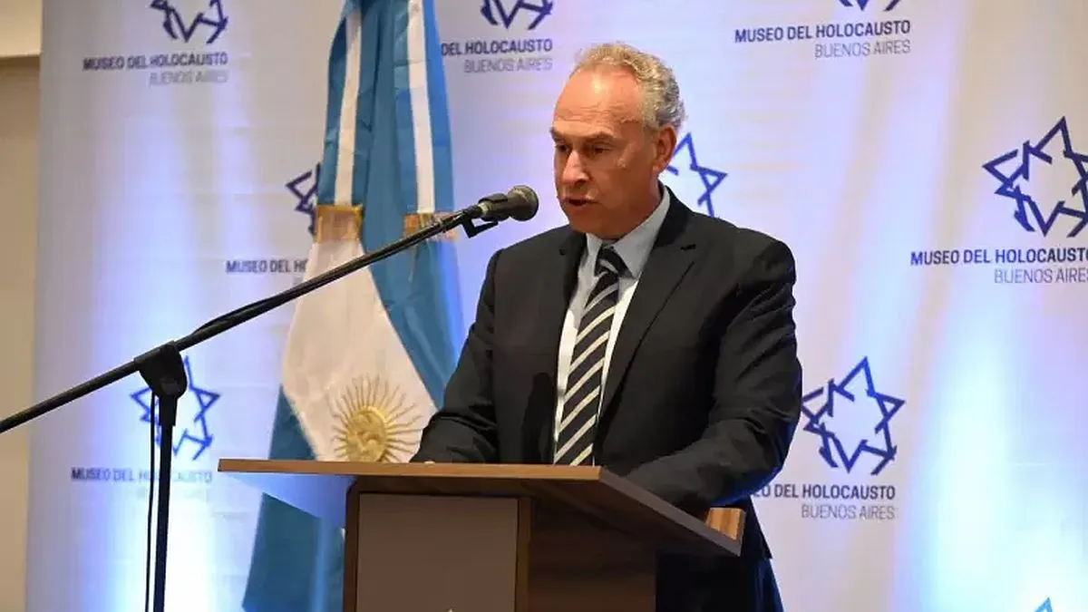 Orador en el Museo del Holocausto de Buenos Aires durante un evento institucional, con una bandera argentina de fondo.