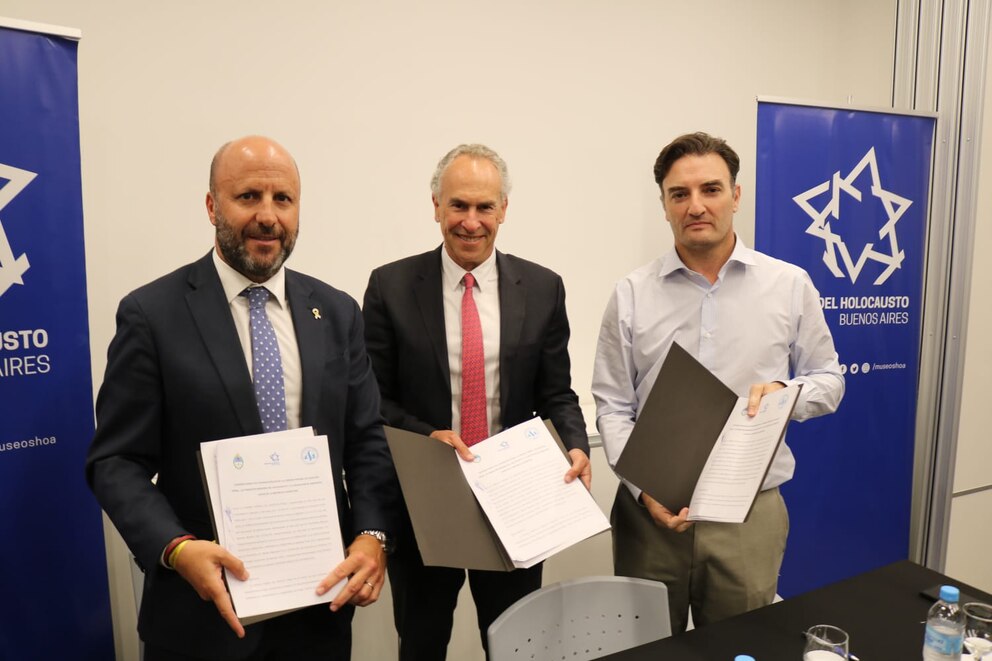 Marcelo Mindlin junto al Museo del Holocausto firma un convenio con AAJRA y CFCP en un evento institucional con representantes sosteniendo documentos frente a banners corporativos.
