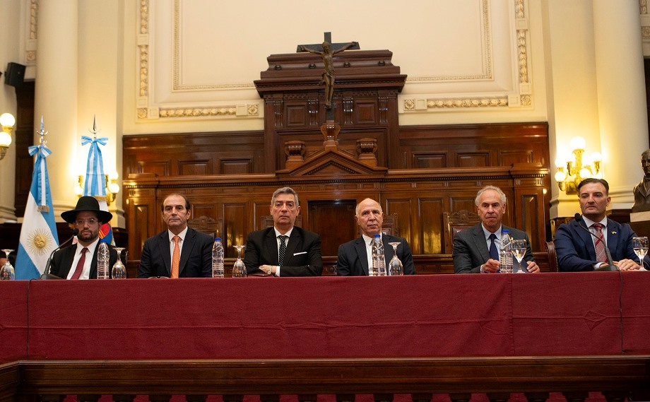 Autoridades en conferencia institucional en un salón oficial, bajo el contexto de MDH, con banderas argentinas y decoración formal.
